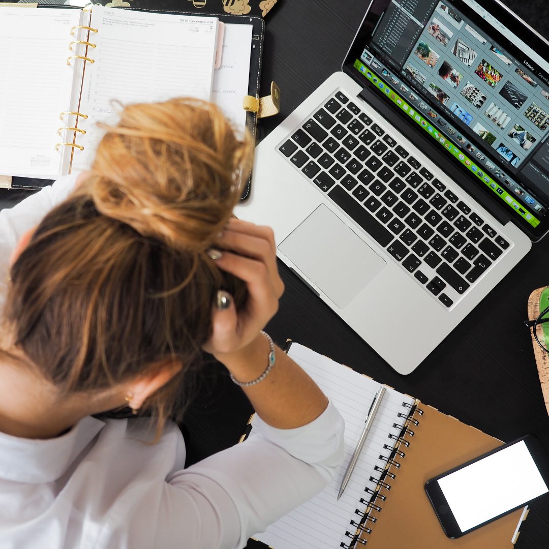 woman with her hair in a bun sat over her desk with financial stress